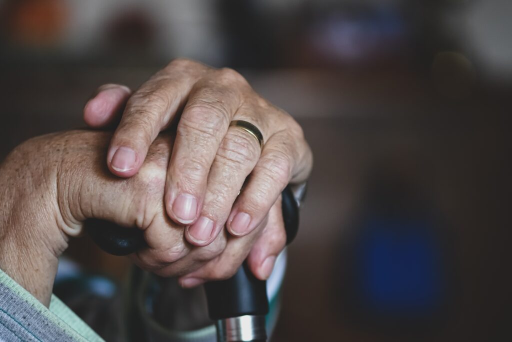Sostegno psicologico agli anziani - mani di persona anziana su un bastone da passeggio